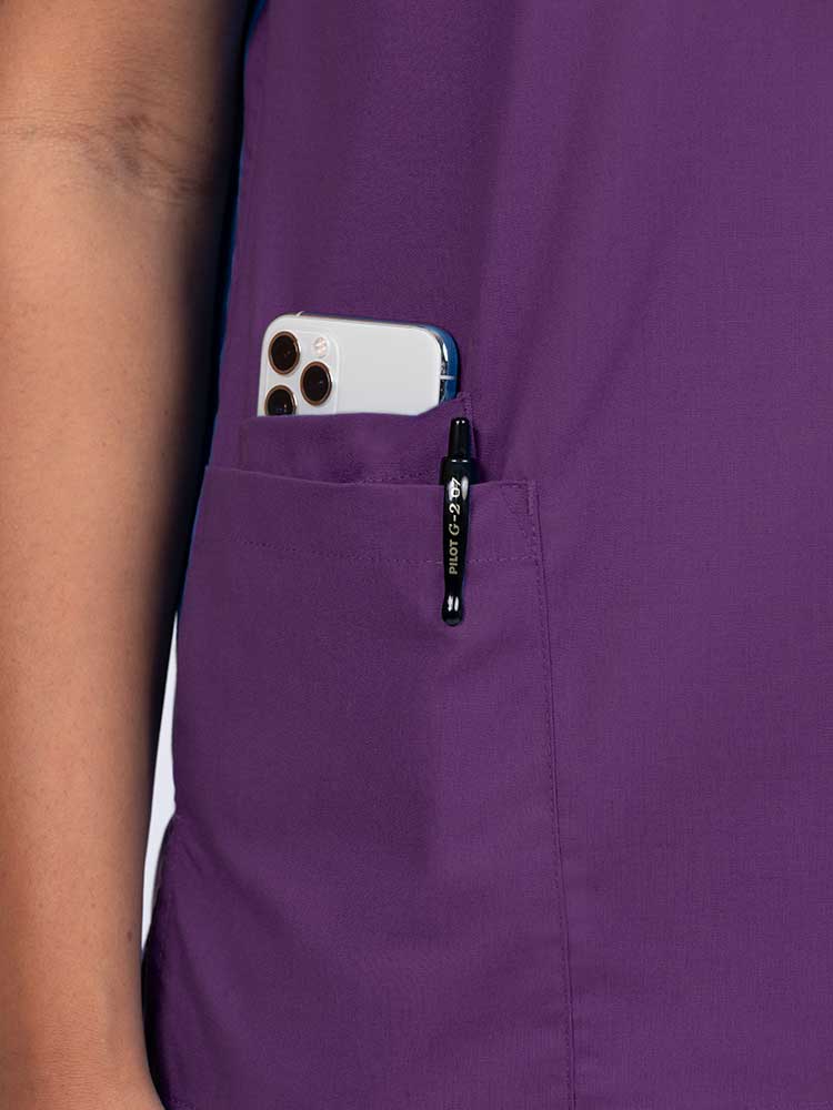 Young female healthcare worker wearing a Luv Scrubs by MedWorks Women's V-neck Scrub Top in eggplant with a hidden utility pocket/pen slot on wearer's right side.