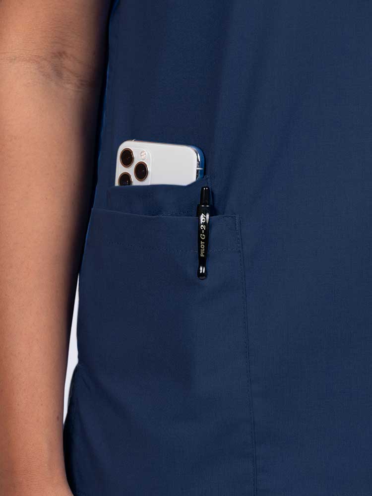 Young female healthcare worker wearing a Luv Scrubs by MedWorks Women's V-neck Scrub Top in navy with a hidden utility pocket/pen slot on wearer's right side.