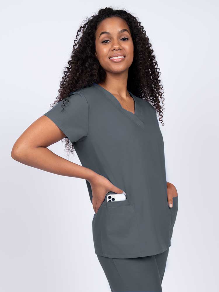 Young nurse wearing a Luv Scrubs by MedWorks Women's V-neck Scrub Top in pewter with featuring short sleeves, and a total of 3 pockets.