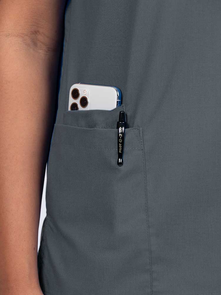 Young female healthcare worker wearing a Luv Scrubs by MedWorks Women's V-neck Scrub Top in pewter with a hidden utility pocket/pen slot on wearer's right side.