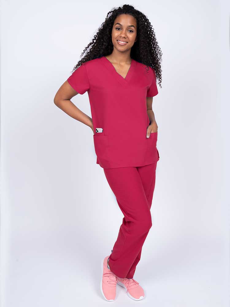Woman wearing a Luv Scrubs by MedWorks Women's V-neck Scrub Top in red with 2 front patch pockets.