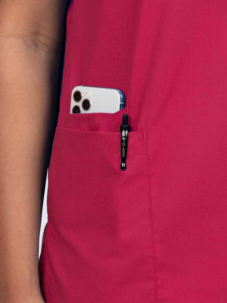 Young female healthcare worker wearing a Luv Scrubs by MedWorks Women's V-neck Scrub Top in red with a hidden utility pocket/pen slot on wearer's right side.