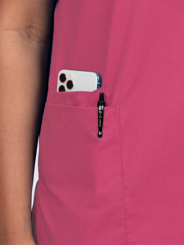 Young female healthcare worker wearing a Luv Scrubs by MedWorks Women's V-neck Scrub Top in shocking pink with a hidden utility pocket/pen slot on wearer's right side.