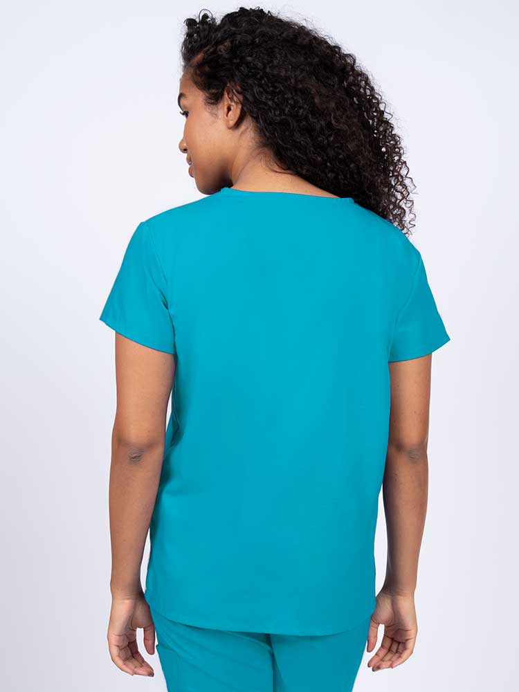 A young female Anesthesiologist wearing a Luv Scrubs by MedWorks Women's V-Neck Scrub Top in Turquoise size medium featuring a center back length of 26".