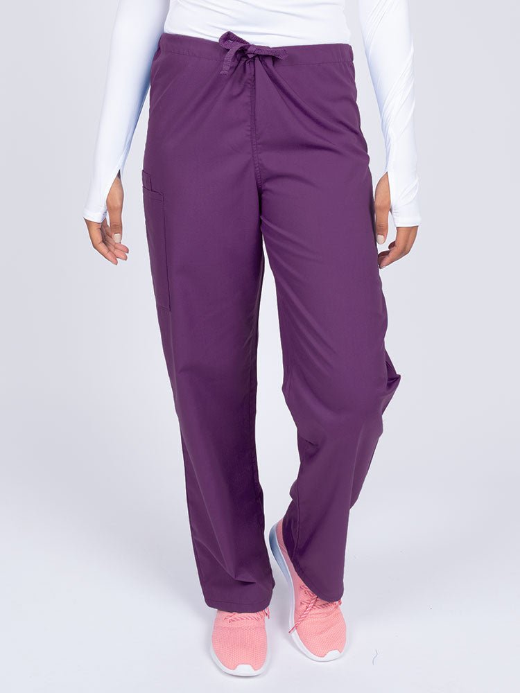 Young nurse wearing a Luv Scrubs Unisex Drawstring Cargo Pant in eggplant with a total of 3 pockets.
