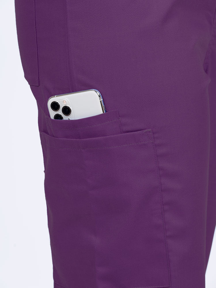 Female nurse wearing a Luv Scrubs Unisex Drawstring Cargo Pant in eggplant with 1 cargo & cell phone pocket on the wearer's right side.