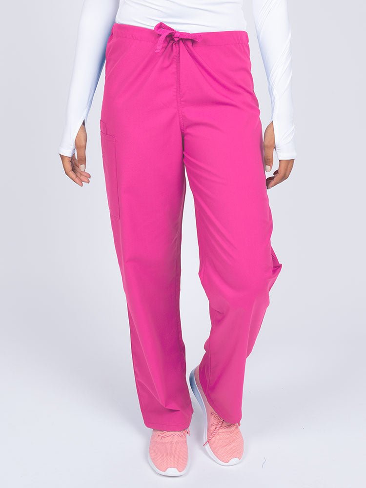 Young nurse wearing a Luv Scrubs Unisex Drawstring Cargo Pant in shocking pink with a total of 3 pockets.