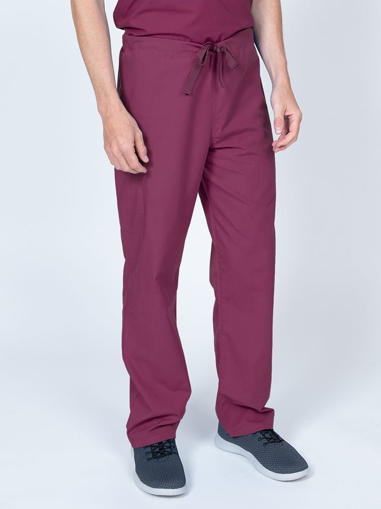 A young male Nurse wearing a Luv Scrubs Unisex Drawstring Cargo Pant in wine with an inseam of 31".