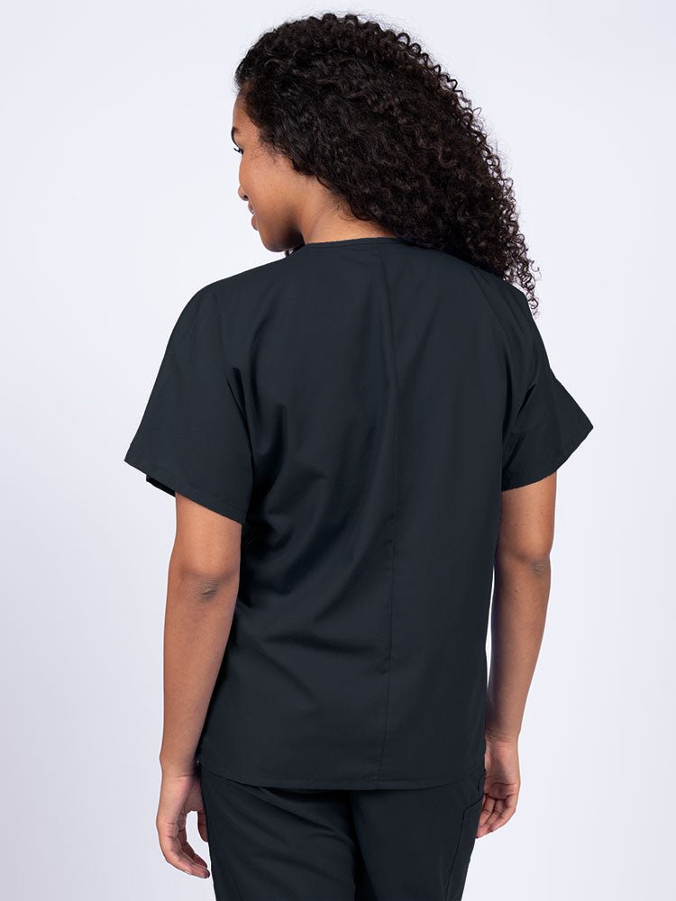 A young female Nurse wearing a Luv Scrubs Unisex Single Pocket V-Neck Scrub Top in Black with a center back length of 27.5".