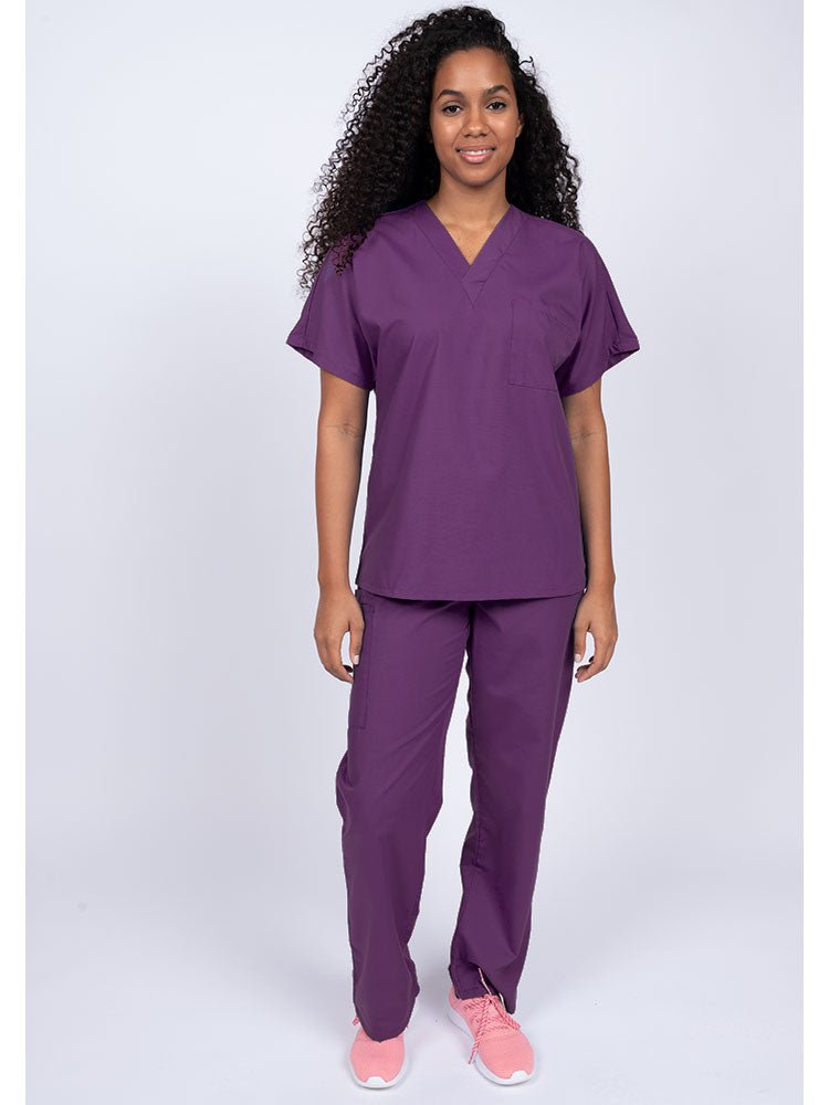 A young female Physical Therapist wearing a Luv Scrubs Unisex Single Pocket Scrub Top in Eggplant  featuring a V-neckline.