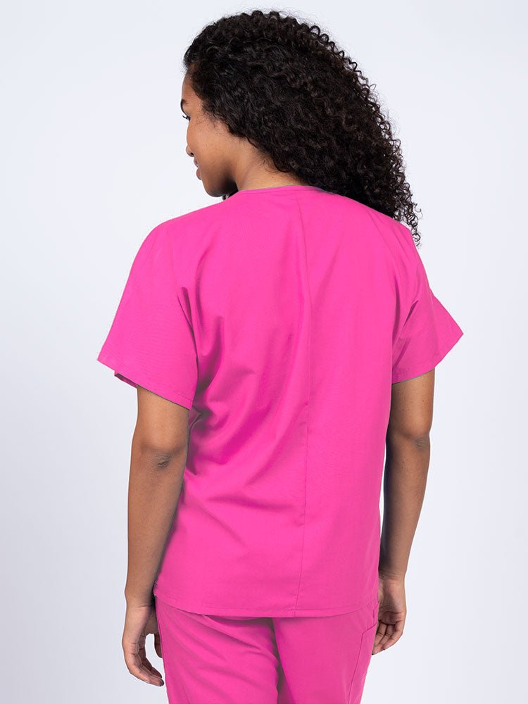 A young female Nurse wearing a Luv Scrubs Unisex Single Pocket V-Neck Scrub Top in shocking pink with a center back length of 27.5".