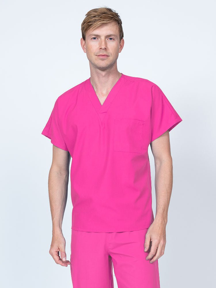 A young male Clinical Laboratory Technologist wearing a Luv Scrubs Unisex Single Pocket V-Neck Scrub Top in shocking pink with dolman sleeves and 1 chest pocket.