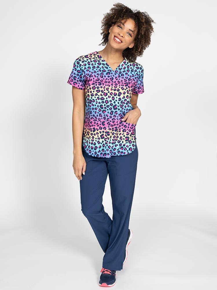 Young woman wearing a Meraki Sport Women's Print Scrub Top in "Animal Motion" featuring 2 front patch pockets.