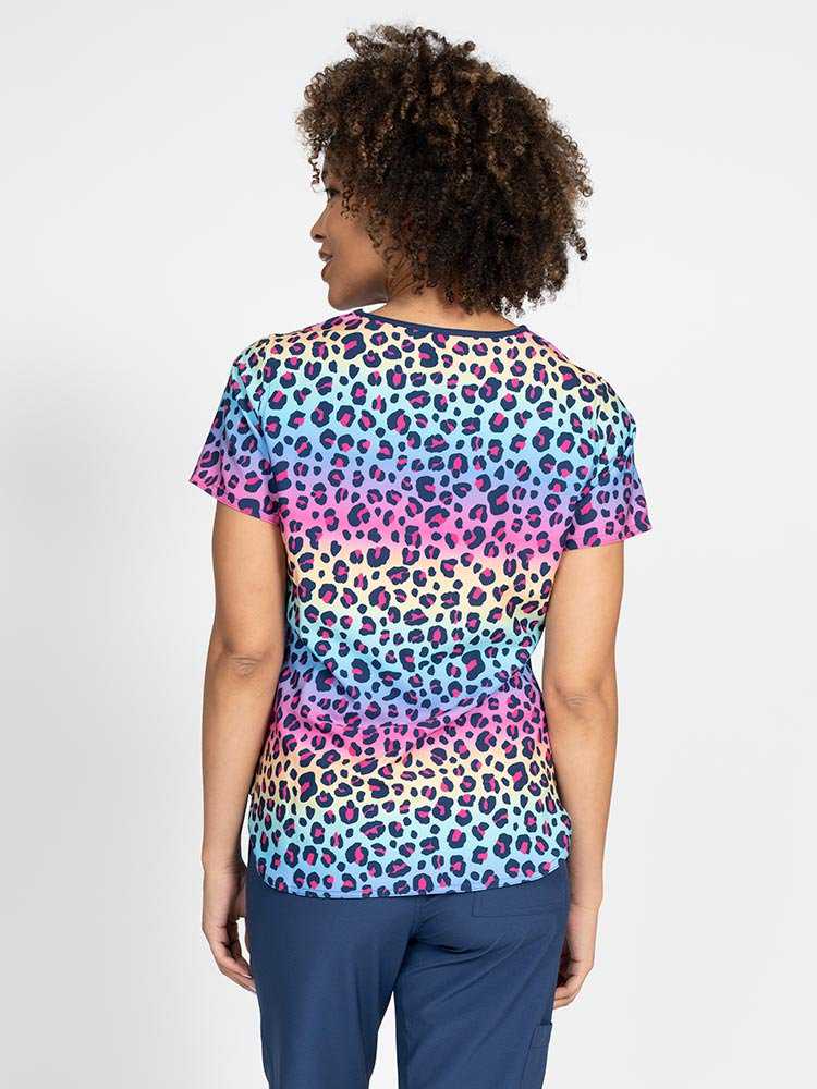 The back of a young Pediatric Nurse wearing a Women's Print Scrub Top in "Animal Motion" from Meraki Sport featuring shoulder yokes for a flattering  fit.