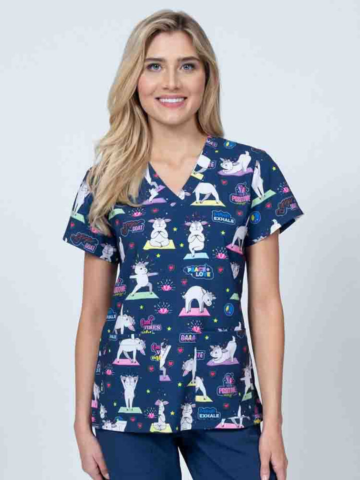 A young female Nurse Practitioner wearing a Meraki Sport Women's Print Scrub Top in "Baa-maste" featuring a v-neckline & short sleeves.