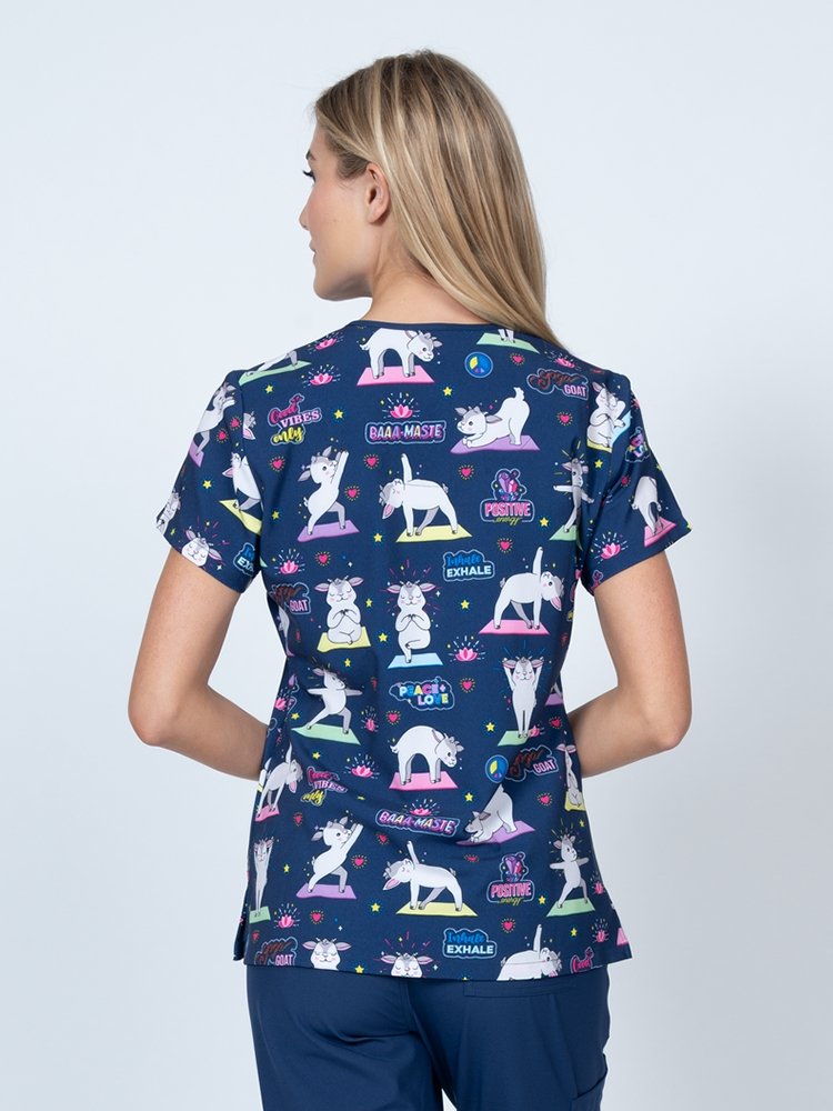 A young lady nurse wearing a Meraki Sport Women's Print Scrub Top in "Baa-maste" featuring shoulder yokes & side slits for additional range of motion.