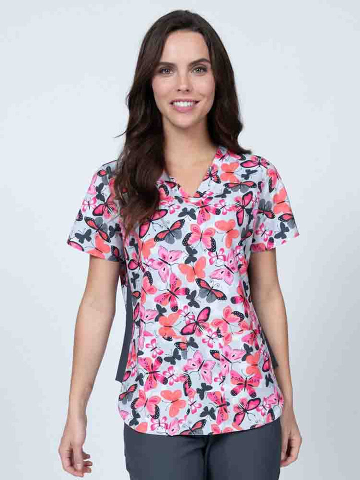 Young healthcare professional wearing a Meraki Sport Women's Print Scrub Top in "Enchanted Spirit" featuring stretch side panels for a comfortable all day fit.