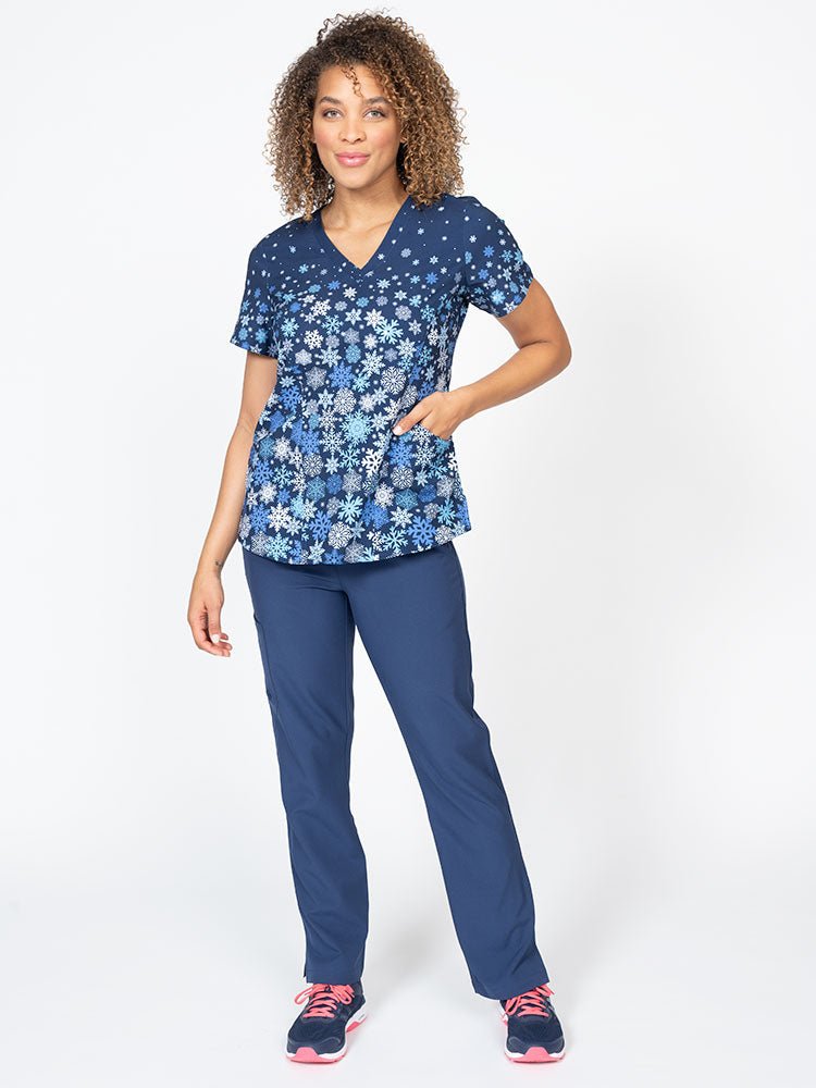 A female LPN wearing a Meraki Sport Women's Print Scrub Top in "Falling Flakes" featuring 2 front patch pockets for all of your on the job storage needs.