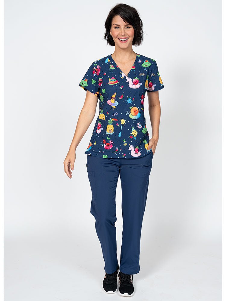 A female LPN wearing a Women's Print Scrub Top from Meraki Sport in "Fruite-tastic" featuring 2 front patch pockets.