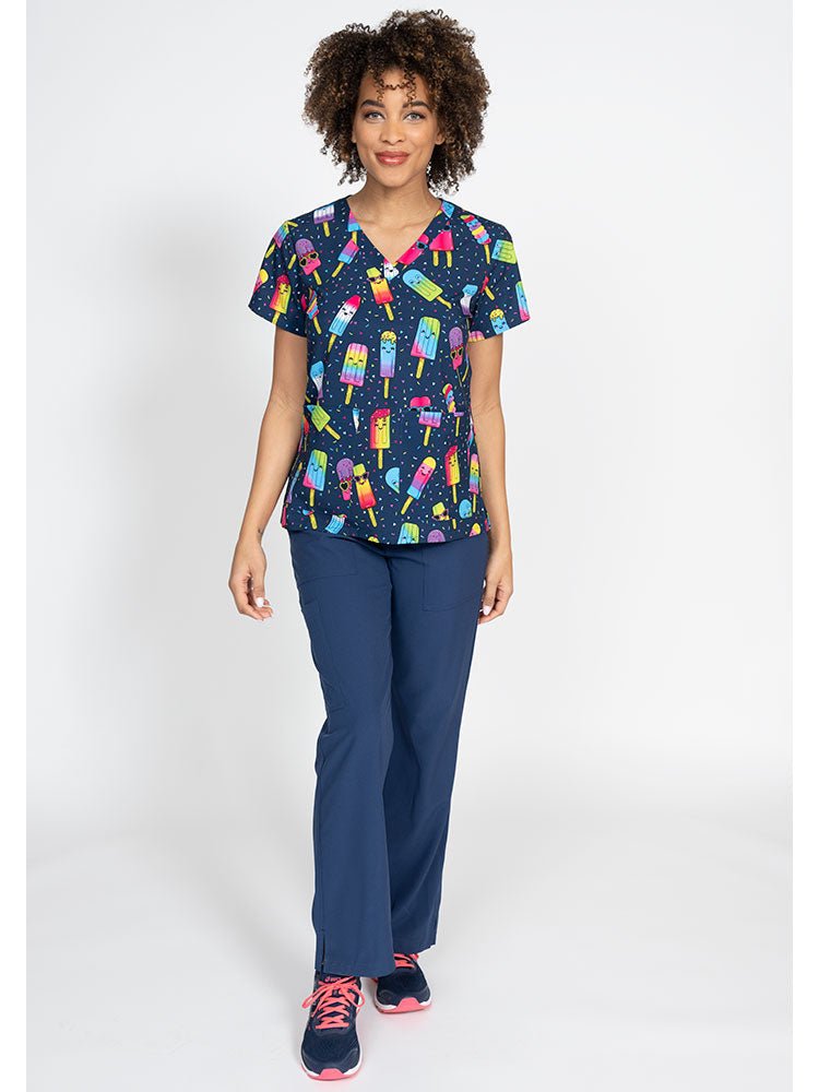 A female LPN wearing a Women's Print Scrub Top from Meraki Sport in "Make Me Melt" featuring 2 front patch pockets.