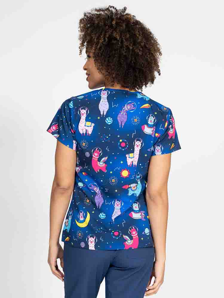 A young lady nurse wearing a Meraki Sport Women's Print Scrub Top in "Space Llama" featuring shoulder yokes & side slits for additional range of motion.