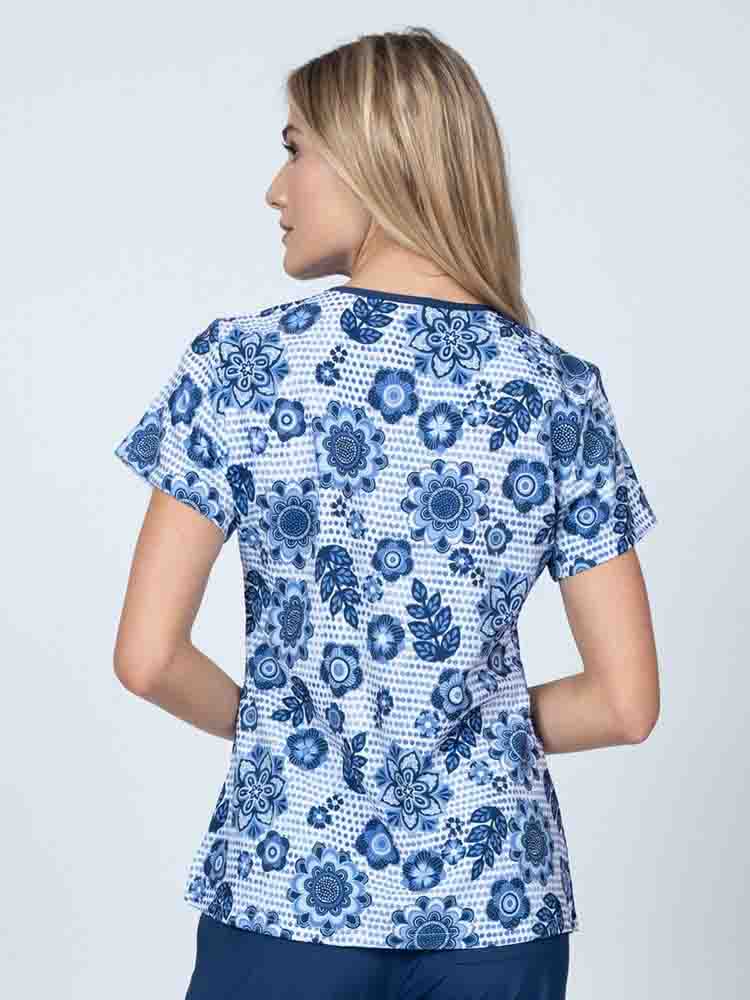 A young lady nurse wearing a Meraki Sport Women's Print Scrub Top in "Summer Blooms" featuring shoulder yokes & side slits for additional range of motion.