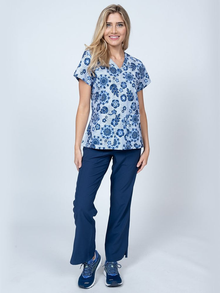 A female LPN wearing a Women's Print Scrub Top from Meraki Sport in "Summer Blooms" featuring 2 front patch pockets.