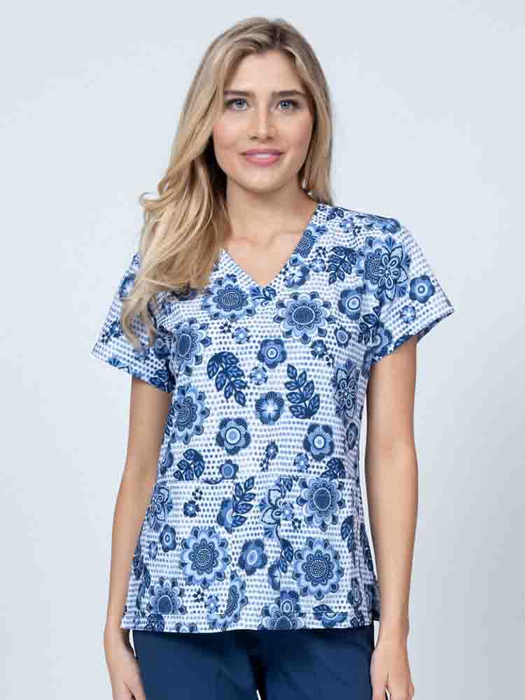A young female Nurse Practitioner wearing a Meraki Sport Women's Print Scrub Top in "Summer Blooms" featuring a v-neckline & short sleeves.