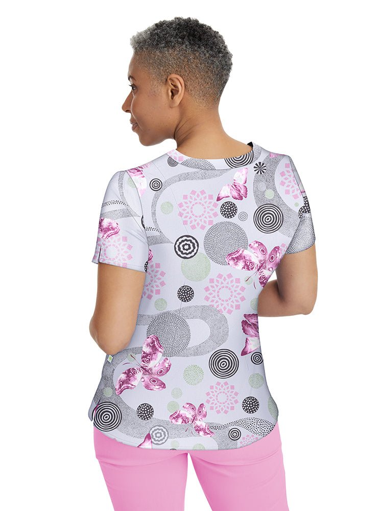 Young nurse wearing a Premiere by Healing Hands Women's Amanda Print Top in "Delightful Spirit" featuring darts at the bust & back shaping darts for a flattering fit.
