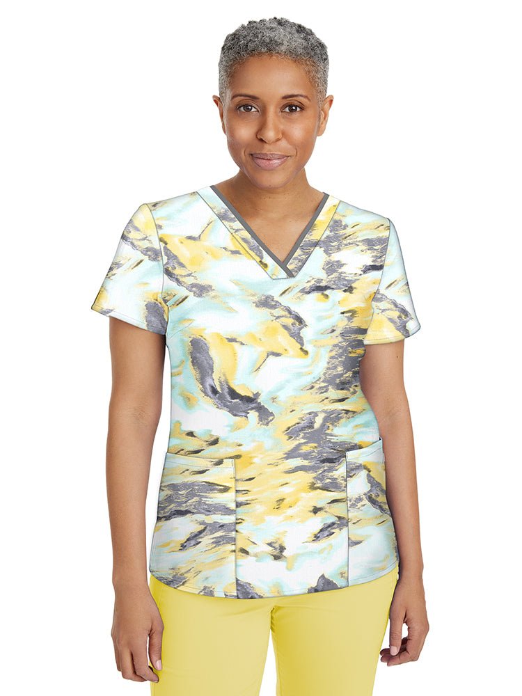 Female nurse wearing a Women's Amanda Print Top from Premiere by Healing Hands in "Liquid Light" featuring 2 front welted pockets & an additional interior pocket.