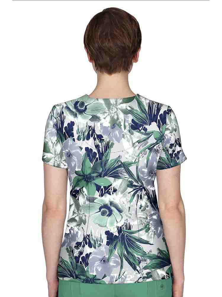 The back of a young female Oncology Nurse wearing a Premiere by Healing Hands Women's Amanda Printed Scrub Top in "Morning Bloom" size Medium featuring a center back length of 26.5".