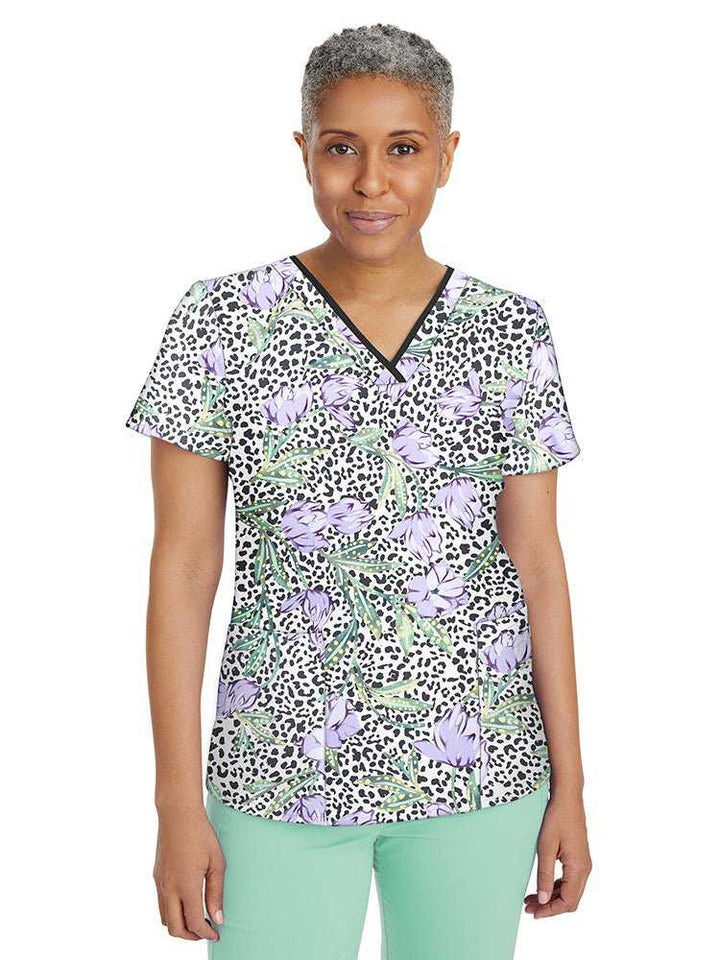 Female nurse wearing a Women's Amanda Print Top from Premiere by Healing Hands in "Wild Beauty" featuring 2 front welted pockets & an additional interior pocket.