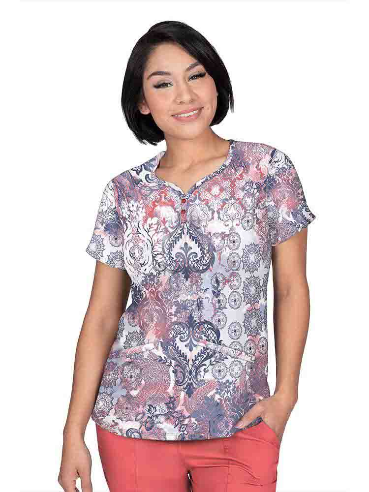A young female Pediatric Nurse wearing a Premiere by Healing Hands Women's Isabel Print Top in "Antique Beauty" size Medium featuring two angled front pockets.