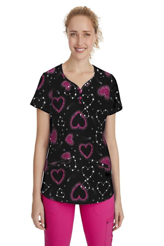 A young female Pediatric Nurse wearing a Women's Isabel Printed Scrub Top in "Love and Beyond" featuring a y-neckline and bust darts.