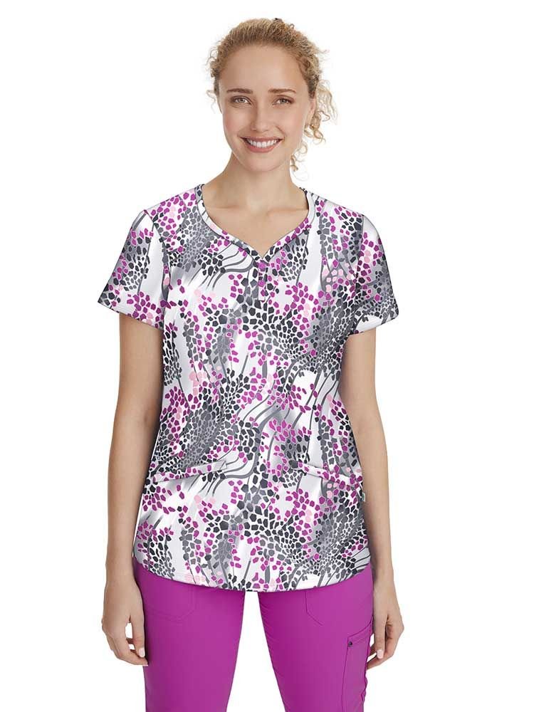 A young female Pediatric Nurse wearing a Women's Isabel Printed Scrub Top from Premiere by Healing Hands in "Modern Safari" featuring a y-neckline and short sleeves.