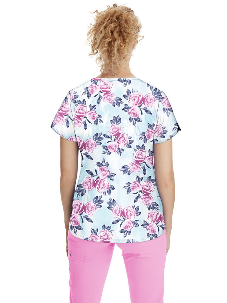 Young nurse wearing a Premiere by Healing Hands Women's Isabel Print Top in "Scent of a Rose" featuring 2 angled front pockets & side slits at the sleeves.