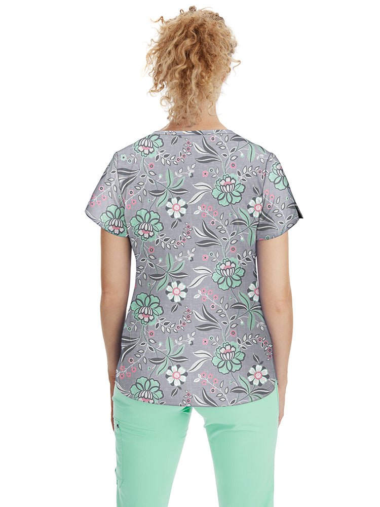 Young nurse wearing a Premiere by Healing Hands Women's Isabel Print Top in "Simply Sweet" featuring 2 angled front pockets & side slits at the sleeves.