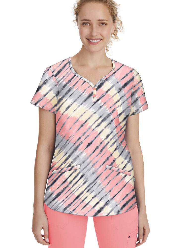 Female healthcare professional wearing a Healing Hands Women's Isabel Print Top in "Tie Dye Wave" featuring a Y-neck with decorative buttons & 2 angled front pockets.