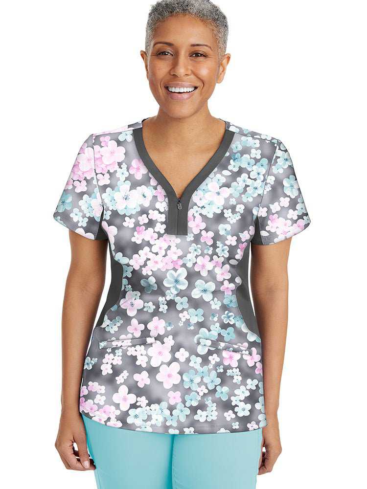 A female nurse wearing a Premiere by Healing Hands Women's Jessi Print Top in "Dreamy Days" featuring 2 Front patch pockets & side vents at the hemline.