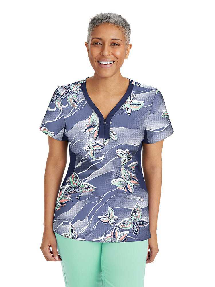 Young nurse wearing a Premiere by Healing Hands Women's Jessi Print Top in "Feeling Free" featuring 2 Front patch pockets & side vents at the hemline.