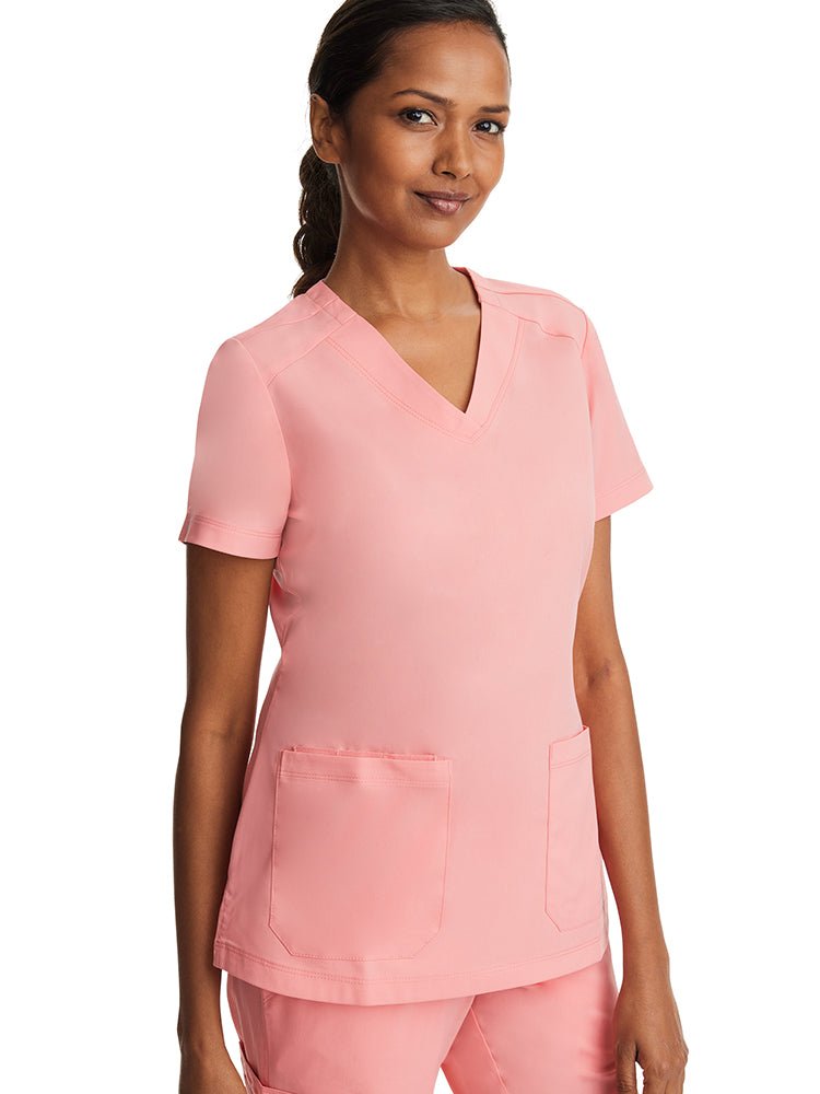 Young female nurse wearing a Purple Label Women's Jill V-Neck Scrub Top in "Melon" featuring 2 front patch pockets.