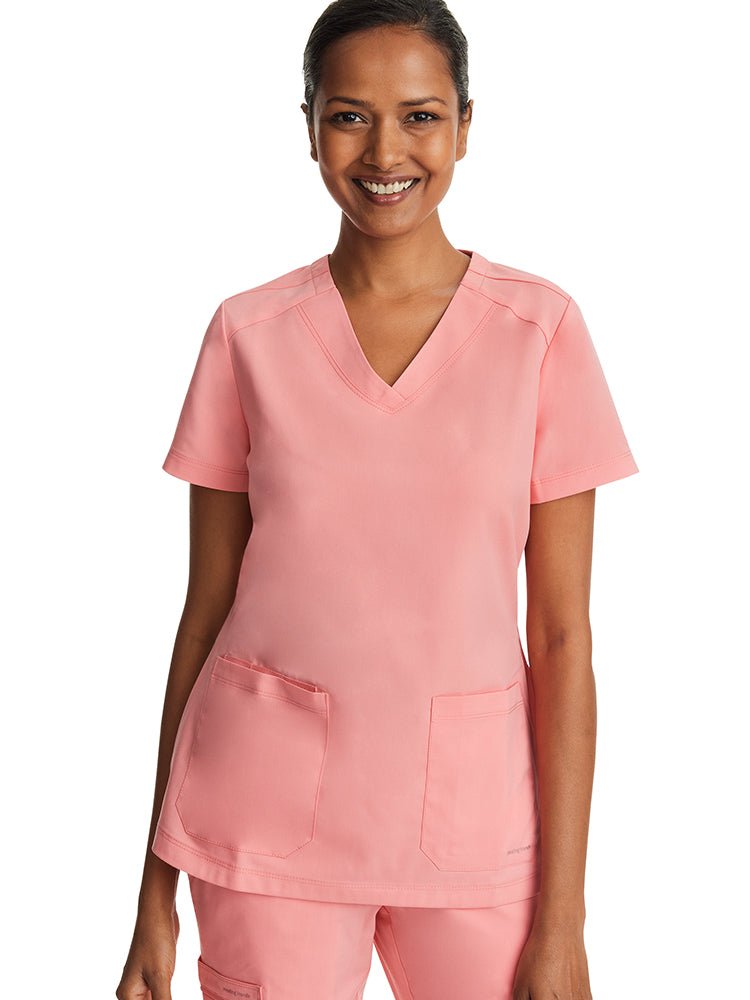 Female nurse wearing a Women's Jill V-Neck Scrub Top from Purple Label by Healing Hands in "Melon".