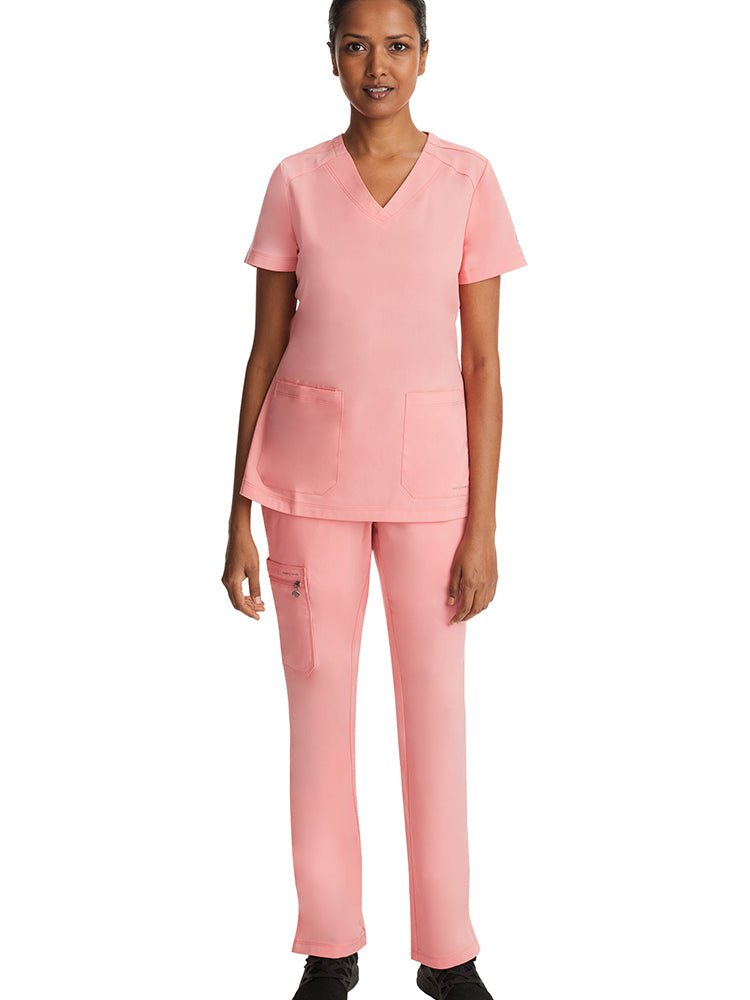 Young woman wearing a Purple Label Women's Jill V-neck Scrub Top in "Melon" featuring 1 interior cellphone pocket.