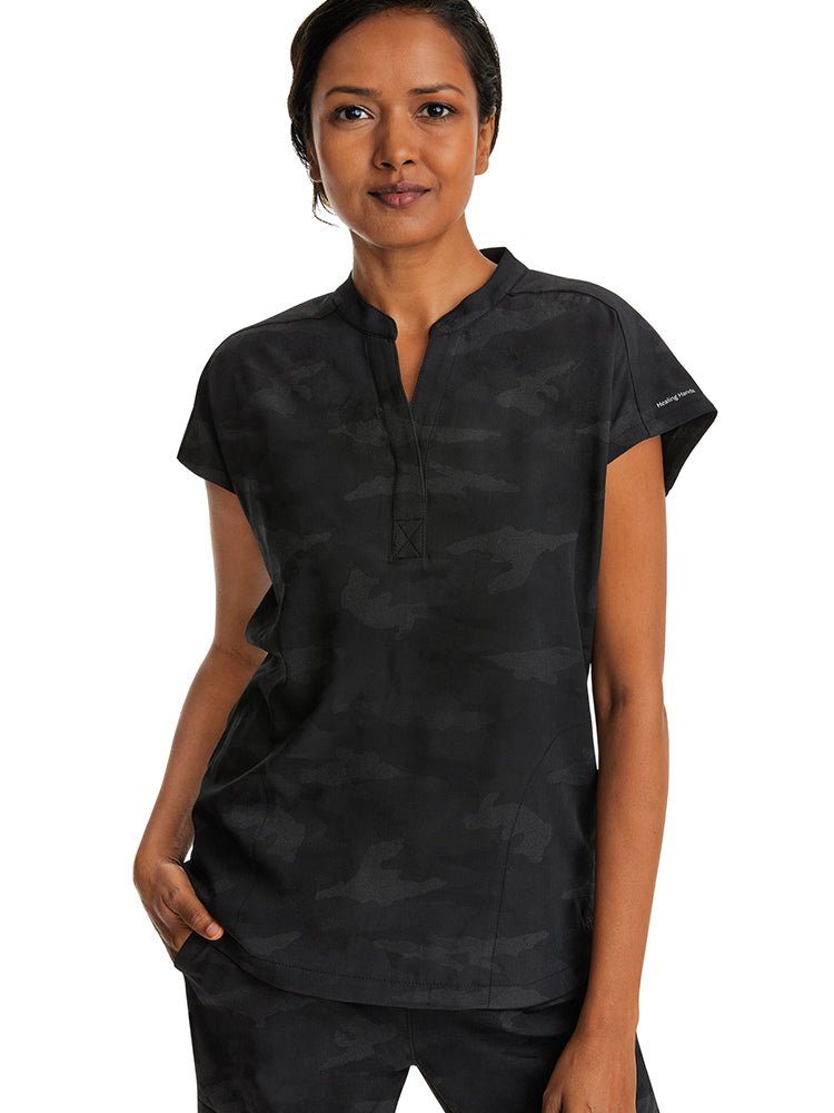 A young female Nurse Practitioner wearing a Products Purple Label Women's Journey Camo Top in Black size Small featuring a modern fit.
