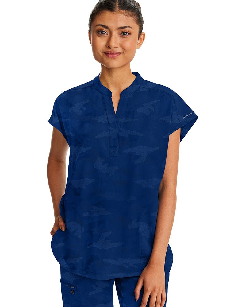 A young female Nurse Practitioner wearing a Products Purple Label Women's Journey Camo Top in Navy size Small featuring a modern fit.