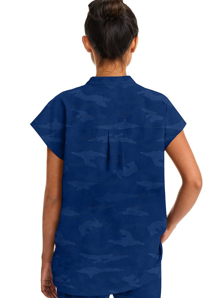 A young female Occupational Therapy Aide wearing a Purple Label Women's Journey Camo Top in Navy size Large featuring a center back length of 26.5".