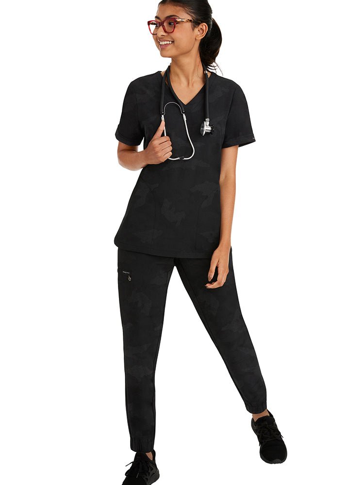 Female healthcare professional wearing a Purple Label Women's Joy Camo Top in black featuring a a super soft, blend of stretch fabric that is quick drying.