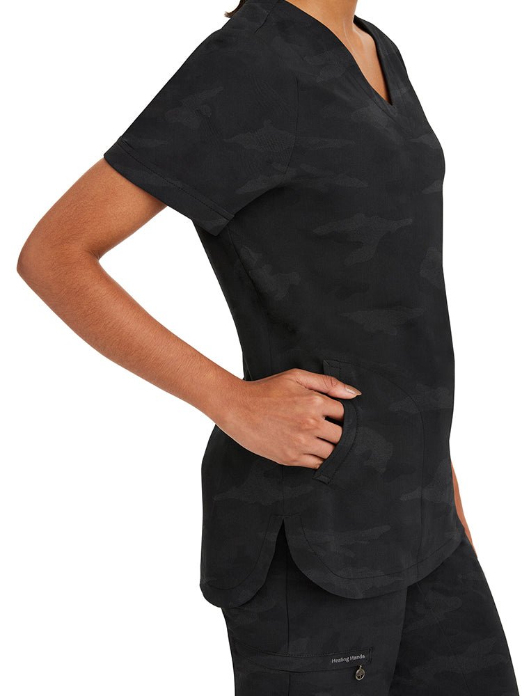 Young nurse wearing a Purple Label Women's Joy Camo Top in black with 2 welt pockets on each side.