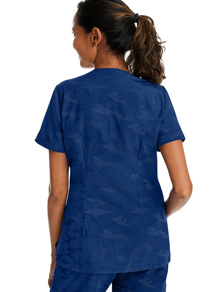 Young woman wearing a Purple Label Women's Joy Camo Top in Navy with folded cuffs at the end of each sleeve.
