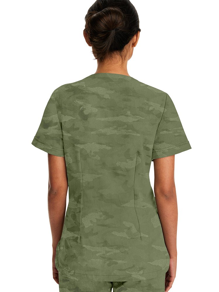 Young woman wearing a Purple Label Women's Joy Camo Top in Olive with folded cuffs at the end of each sleeve.